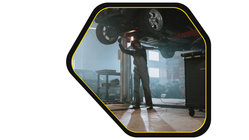 Ein Mechaniker in einer kfz werkstatt, der ein Auto repariert.